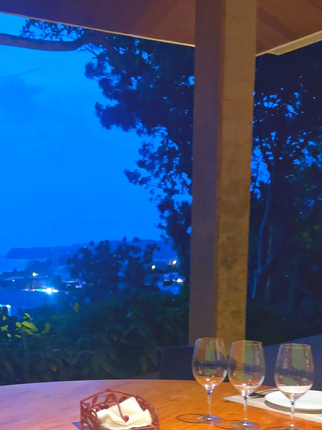 Table set for dinner at dusk, with the lights of the coast below