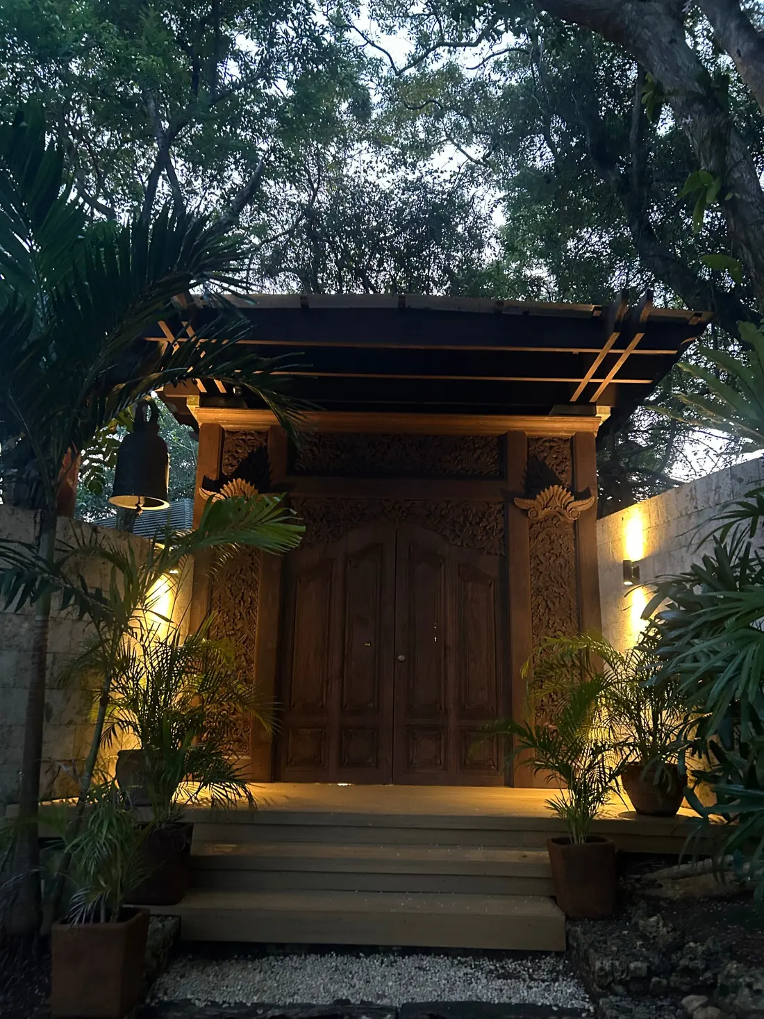 Carved wooden entrance gate lit at dusk